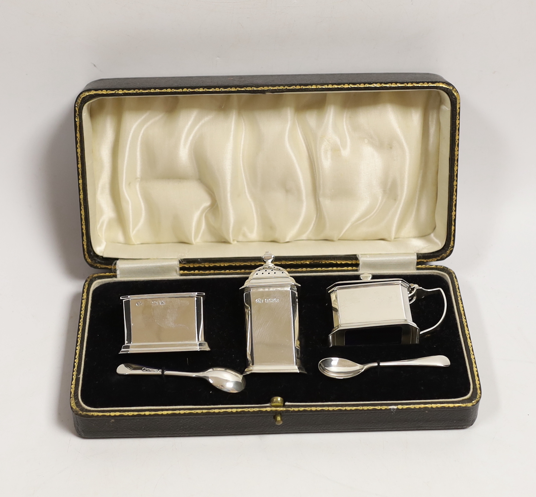 A cased George VI silver three piece condiment set, Elkington & Co, Birmingham, 1936 and two spoons, one matching silver, the other plated replacement.